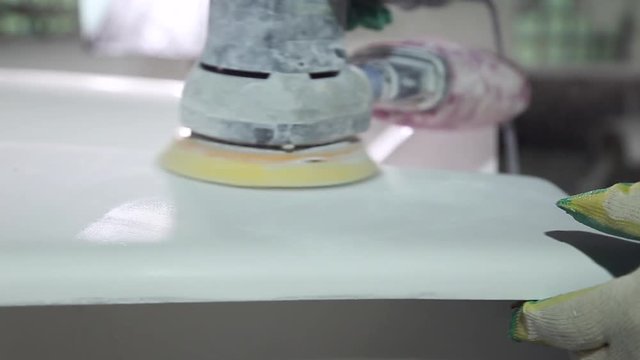 Construction of plastic boats, master grinds a sander plastic boat