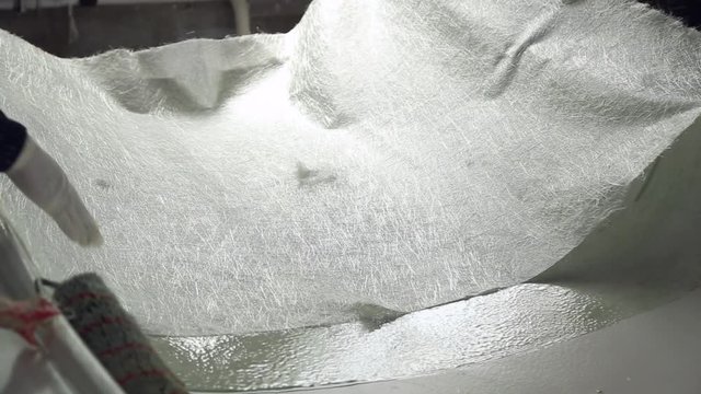 Construction of plastic boats, workers stick the fiberglass on plastic surface