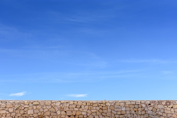 Stone wall and blue sky with clouds, background free space for text