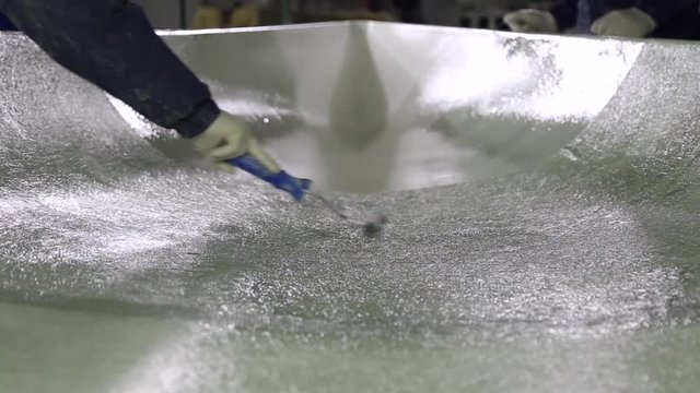 Construction of plastic boats, workers stick the fiberglass on plastic surface using the rollers