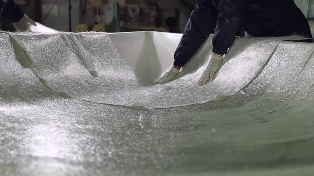 Construction of plastic boats, workers stick the fiberglass on plastic surface
