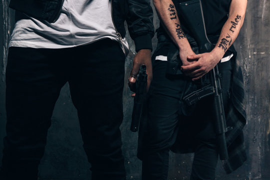 Group of unrecognizable criminals with guns. Armed gangsters with tattoo on dark background. Outlaw, ghetto, murderer, robbery concept
