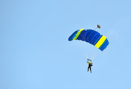 Paracadutista in atterraggio con cielo nuvoloso azzurro