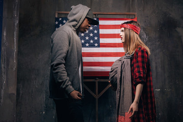 Fototapeta na wymiar US parents in quarrel. Man and woman in conflict. Divorce in american family. Wife and husband with little baby on USA national flag background. Social problem, child custody, youth pregnancy concept