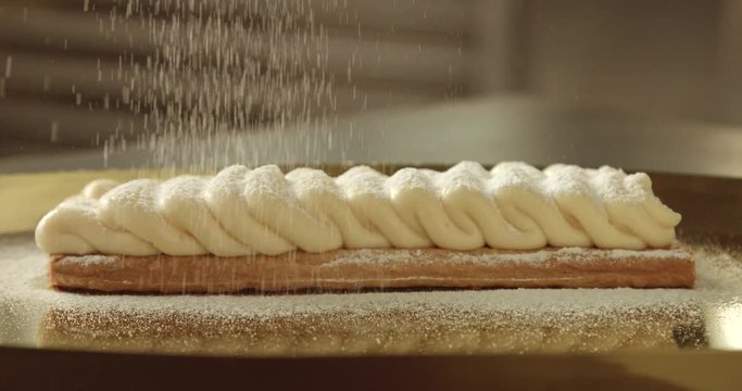 sugar powder falling on a cream on puff pastry base