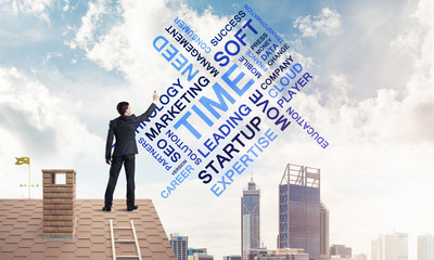 Young businessman standing on house roof and writing leadership 