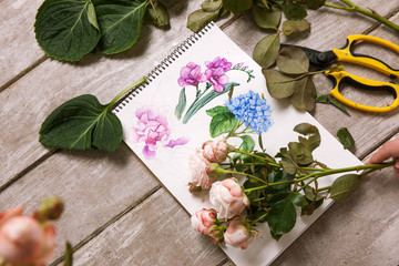 Workplace of decorator, florist. Sketch of flower top view. Professional tools. Floristry workshop wooden table with decor. Decorative watercolor artwork