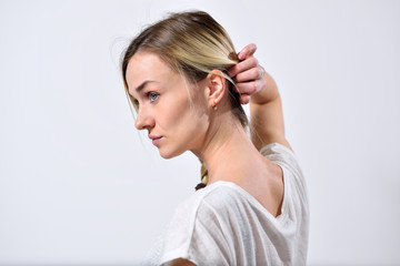 Fototapeta premium Blond girl showing ear and neck pulling back hair