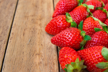 Ripe organic strawberries scattered on plank wood background, close up, low angle, healthy food, cleansing