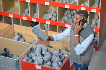 Man on telephone holding plumbing fittings