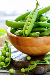 Pods of sweet peas in a wooden bowl.