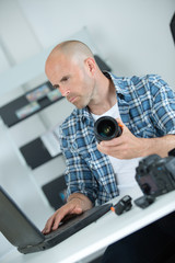 Technician using laptop and holding camera lens