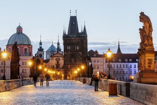 Charles bridge, twilight scenery, street lights visible. Prague iconic travel destination, Czech Republic.