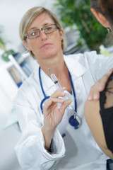 Nurse preparing injection for woman's arm