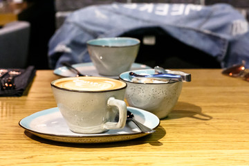 Cup of cappuccino with a pattern and a sugar bowl with brown and white sugar are on the table