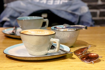 Cup of cappuccino with a pattern and a sugar bowl with brown and white sugar are on the table