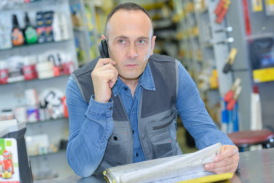 Man looking through stock sheets and talking on telephone