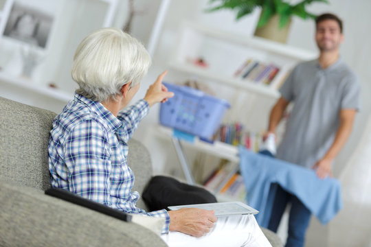 Elderly lady talking to man ironing