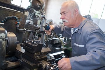 Senior man using air line on machinery