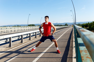 Fototapeta premium Portrait of young athlete man stretching his muscles before running.