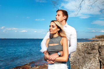 Happy couple on sea background. Happy young couple laughing and hugging on the beach