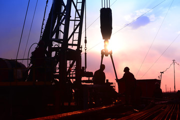 The oil workers in work, under the background of the setting sun