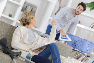 Young man ironing for injured woman