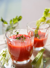 Two glasses of fresh tomato juice with thyme and celery.