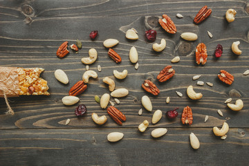 Healthy bar with nuts and seeds on the wooden background, top view