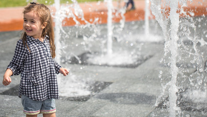 Little girl playing in the fountain