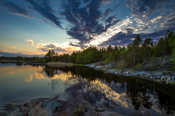 Sunset in the reflection of water. Wild nature of the north. White Nights. Karelia. Ladoga lake. Russia.