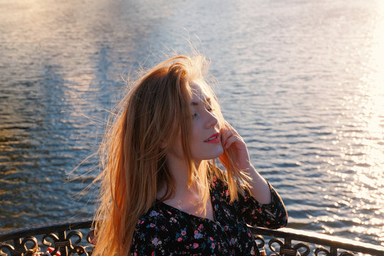 Happy calm woman relaxing in sun light near water