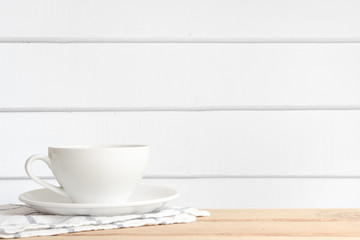 White coffee cup put on wooden in white wood wall room with copy space.
