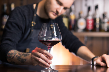 Skilled sommelier pouring wine. Man in black suit and white shirt looks concentrated: he's...