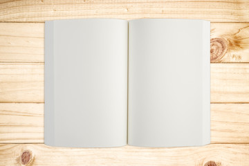 Open white book on wood background.