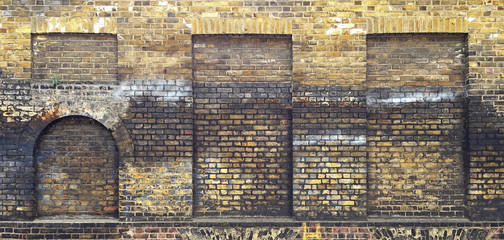 Aged brick wall with four arched bricked up windows with space for text. - 158413052