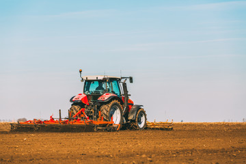 Obraz premium Farmer in tractor preparing land with seedbed cultivator as part of pre seeding activities in early spring season of agricultural works at farmlands.