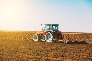 Obraz premium Farmer in tractor preparing land with seedbed cultivator as part of pre seeding activities in early spring season of agricultural works at farmlands.