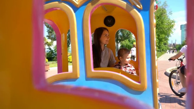 Son with mom riding a child's train.