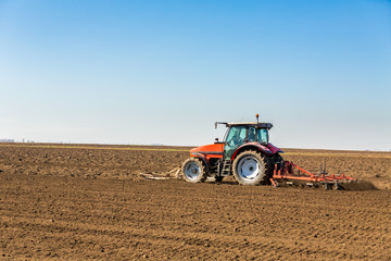 Fototapeta premium Farmer in tractor preparing land with seedbed cultivator as part of pre seeding activities in early spring season of agricultural works at farmlands.