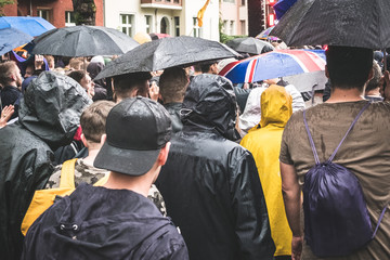 Group of people from behind walking in rain  with umbrellas - rainy weather  - Powered by Adobe