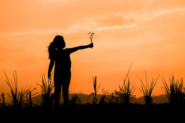 Girl standing on the meadow at sunset