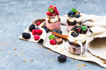 Assortment of creamy gourmet strawberry desserts layered in decorative patterns in individual glass containers