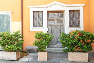 Fototapeta na wymiar The old entrance door and window with shutters in the wall of an ancient house. Towm on Lake Garda is the largest in Italy. It is located in NorthernItaly