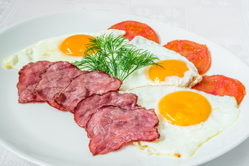 Tasty breakfast. Pieces of bacon, fried eggs and tomatoes with herbs. Horizontal frame