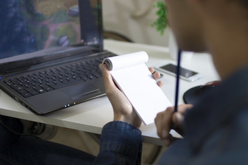 young man studying and working with the computer taking notes