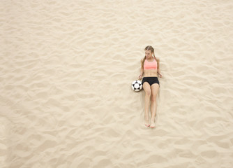 Fototapeta na wymiar young sportswoman with ball lay on sand