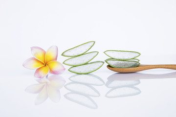 Fototapeta na wymiar Spa concept background, Aloe vera slice in wooden spoon with flower on white background