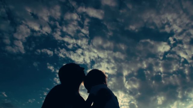 Silhouette of father throwing his son in the air, against the sky