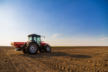 Obraz premium Farmer fertilizing arable land with nitrogen, phosphorus, potassium fertilizer